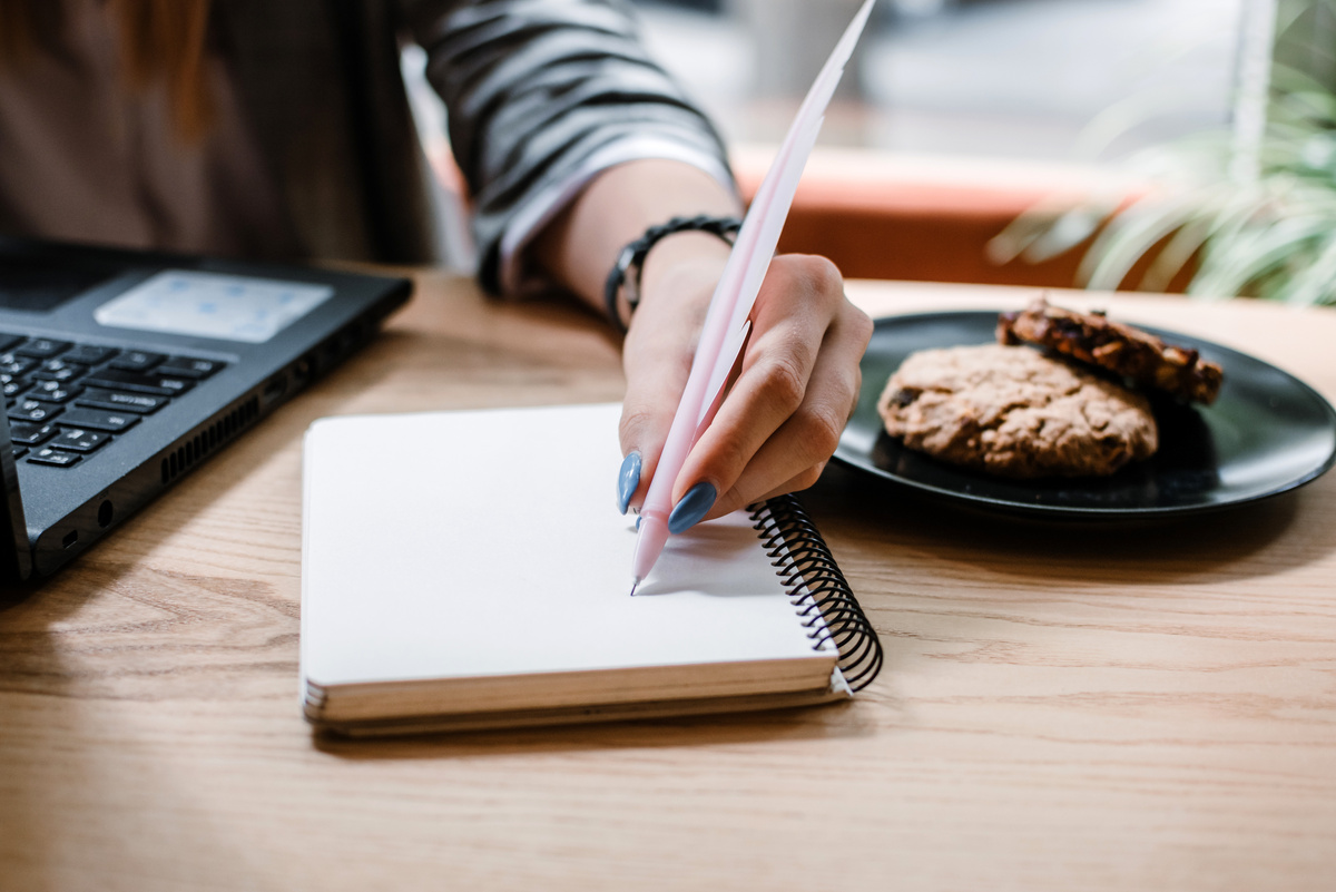 Person Writing on a Notebook Closeup